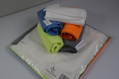 A stack of rolled up microfiber cloths (white, blue, orange, neon green, and dark gray) sit on top of the unopened package of the five microfiber cloths.