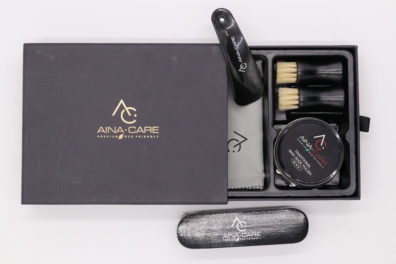 Aerial view of the Premium II Shoe Polish Kit that's slightly opened to show two brushes, a wax polish tub, and a microfiber cloth all from AinaCare.