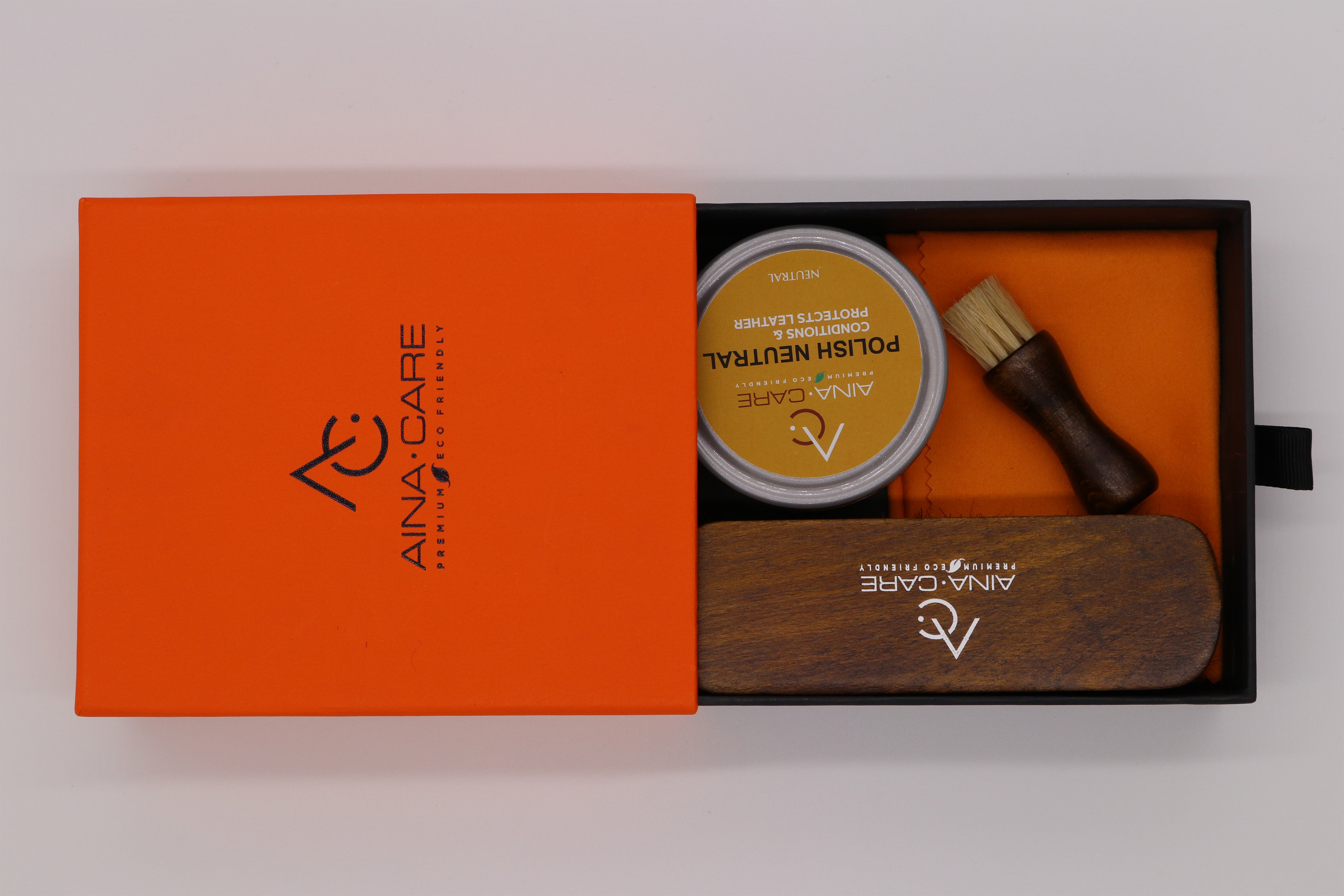 Aerial view of an opened Premium I Shoe Polish Kit from AinaCare showing all of the included products on a white background. 